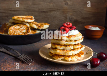 Rustikale hausgemachten Quark Pfannkuchen zum Frühstück, Landhausstil mit Joghurt-Sauce und Kirsche. Gesundes Essen rustikal, Pfannkuchen Quark. Stockfoto