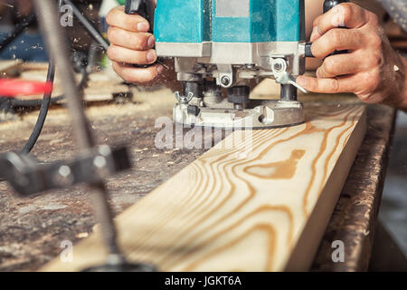 Eine Nahaufnahme einer Holzplatte mit einem grünen Fräsmaschine auf einem Holztisch Stockfoto