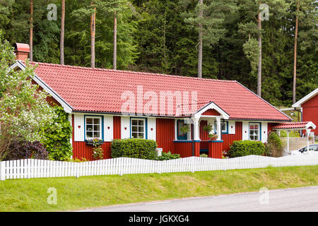 Typisch schwedischen roten Holzhaus mit weißen Garnituren neben einem Wald Model Release: Nein Property Release: Nein Info: Photograph Verständnis (aber nicht garantiert) ist, dass Eigentum Freigabe ist nicht für private Eigenschaften für die gewerbliche Nutzung nach dem schwedischen Gesetz für Bilder aus öffentlichen Land-/Straße genommen. Bild von der öffentlichen Straße genommen. Stockfoto