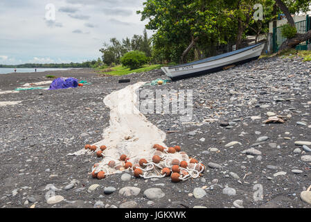 Saint-Paul, Réunion, Frankreich - 24. Dezember 2015: Fischernetze am schwarzen Strand Trocknung und Angelboot/Fischerboot in Saint Paul auf der Insel La Reun Stockfoto