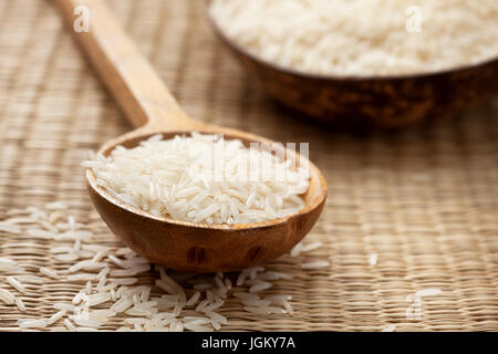 Basmati-Reis in Holzlöffel auf Stroh Hintergrund Stockfoto