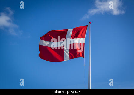 Dänische Flagge bei Sonnenschein gegen blauen Himmel mit Wolken, horizontale Stockfoto