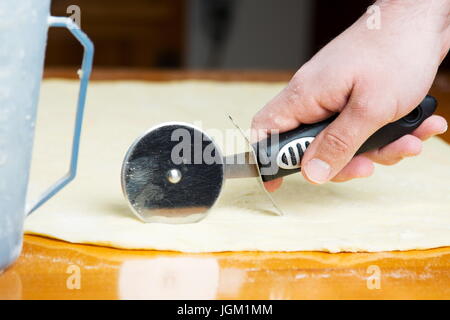 Mann schneiden Teig mit einem Roller-Messer Stockfoto