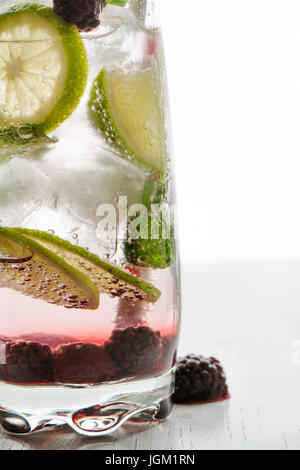 Gin Tonic cocktail mit Limetten, Eis und roter Frucht, weißen Hintergrund. Nahaufnahme Stockfoto