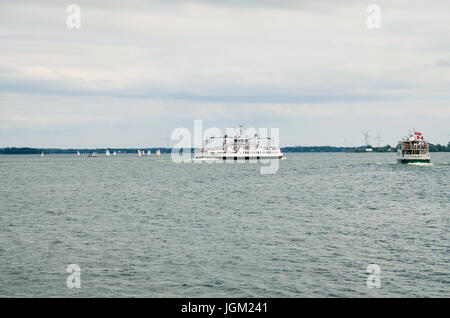 Kingston, Kanada - 23. Juli 2014: Canadian Tourboote, Frachtschiffe und Windkraftanlagen im Sankt-Lorenz-Strom Stockfoto