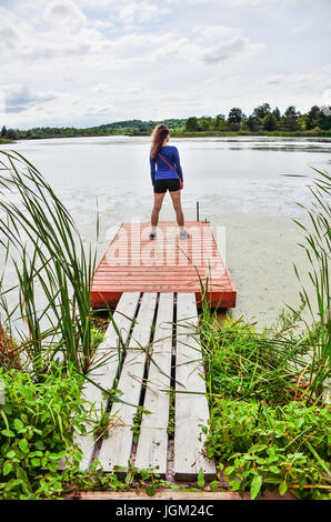 Junge Frau am kleinen Hafenbecken mit Blick auf See Stockfoto