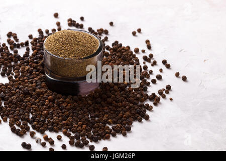Schwarze Pfefferkörner und Pulver auf weißen Stein Hintergrund, Ansicht von oben Stockfoto