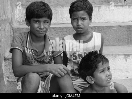 Varanasi, Indien - 12. Juli 2015. Unbekannten jungen in einem indischen Dorf glücklich sitzen auf Stufen und Blick in die Kamera, Varanasi, Indien. Stockfoto