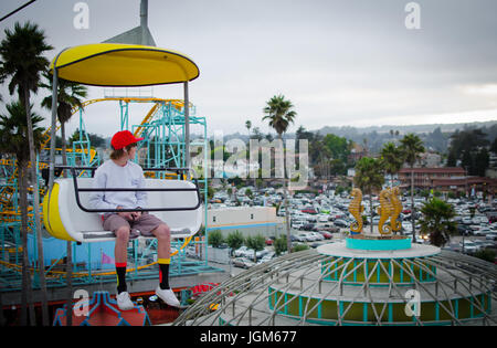 Junge sitzt in einem Wagen auf dem Santa Cruz Beach Boardwalk Skyglider Stockfoto