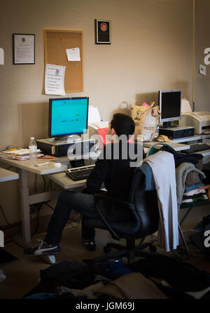 Mann, der an einem Computer sitzt und arbeitet. Stockfoto