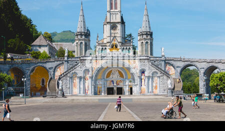 Lourdes, Frankreich, 22. Juni 2017 - Touristen zu Fuß vor der Kathedrale im Heiligtum von Lourdes, Frankreich Stockfoto