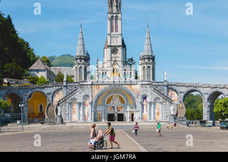 Lourdes, Frankreich, 22. Juni 2017 - Touristen zu Fuß vor der Kathedrale im Heiligtum von Lourdes, Frankreich Stockfoto