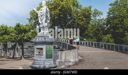 Lourdes, Frankreich, 22. Juni 2017 - Touristen gehen in den Garten des Münsters im Heiligtum von Lourdes, Frankreich Stockfoto