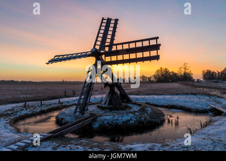 Tsjaker in der Nähe von Kalenberg bei Sonnenaufgang im Winter mit Schnee, Bäume und Graben im Nationalpark De Weerribben-Wieden in den Niederlanden. Stockfoto