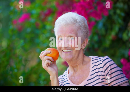 gesunde ältere Frau mit weißen Zähnen essen Apfel. Stockfoto