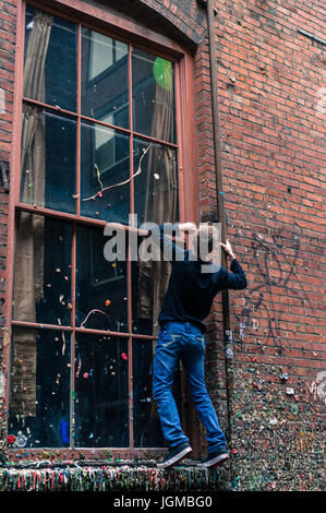 Junge klettert auf eine Fensterleiste in der Gummiwand von Seattle. Stockfoto