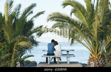 Mädchen lehnte sich auf die Schulter des Jungen unter der Palme Stockfoto