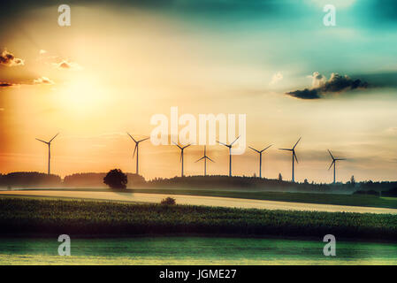 Surreale Morgen Sonnenaufgang auf den Feldern mit Windkraftanlagen im Hintergrund. Stockfoto
