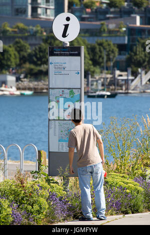 Touristen auf der Suche auf einer Karte im False Creek auf dem Meer Greenway (Deich), Vancouver, Kanada Stockfoto