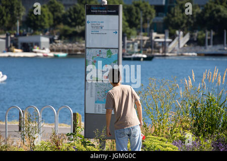 Touristen auf der Suche auf einer Karte im False Creek auf dem Meer Greenway (Deich), Vancouver, Kanada Stockfoto