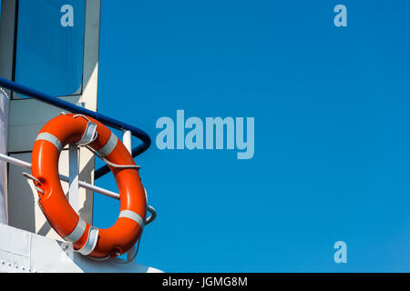 Leuchtend orange Rettungsring auf eine weiße Yacht-Seite. Blauer Himmelshintergrund Stockfoto