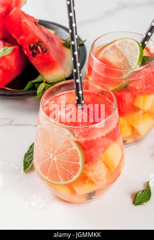 Sommer-Drinks und Cocktails. Limonade, hausgemachte Sangria mit frischen Wassermelone, Limette, Minze und Ananas. In zwei Gläser, auf einem weißen Marmor Tisch. COP Stockfoto