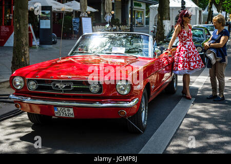 BERLIN - 17. Juni 2017: Muscle-Car Ford Mustang Cabrio, 1965 und eine Frau in einem 60er Jahre Kleid. Classic Days Berlin 2017. Stockfoto