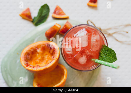 Saft von blutroten Orangen, frisches Obst, auf grüner Minze Tisch von oben Stockfoto