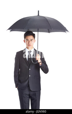 junge asiatische Geschäftsmann in Abendgarderobe hält einen Blick in die Kamera mit einer Hand in der Tasche, Schirm isoliert auf weißem Hintergrund. Stockfoto