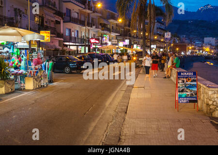 GIARDINI NAXOS, Italien - 28. Juni 2017: Touristen in der Nähe von Souvenirläden an Uferpromenade in Giardini-Naxos-Stadt in Sommernacht. Giardini Naxos ist Badeort Stockfoto