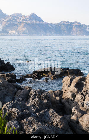 Reisen Sie nach Sizilien, Italien - vulkanischen Gesteinen an der Küste des Ionischen Meeres in Giardini Naxos-Stadt im Sommer Stockfoto