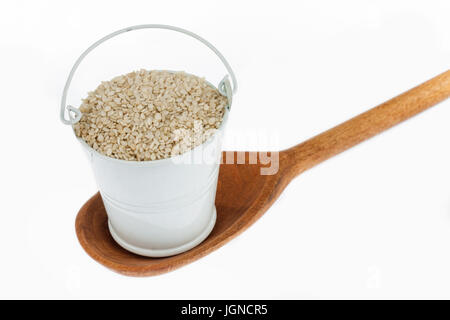 Vollen Eimer mit Sesam-Körner steht in einem Holzlöffel. Das Konzept von Lebensmitteln. Stockfoto