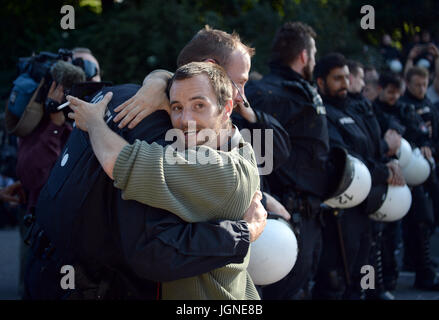 Hamburg, Deutschland. 8. Juli 2017. Ein Demonstrator und ein Polizist hug während einer Demonstration am Millerntor-Platz in Hamburg, Deutschland, 8. Juli 2017. Der zweitägige Gipfel, ein Treffen der Staats-und Regierungschefs der 20 größten Volkswirtschaften der Welt sowie Vertreter einer Vielzahl von internationalen Institutionen endet heute. Foto: Christophe Gateau/Dpa/Alamy Live News Stockfoto