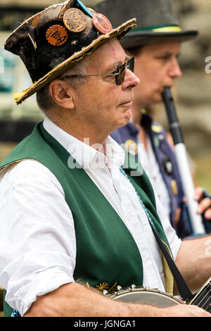 Kaukasische Mann, 40s, Folk Musiker, spielen Banjo mit Flöte Spieler (unscharf) neben ihm aus der Maldon Greenjackets Morris Seite. Stockfoto