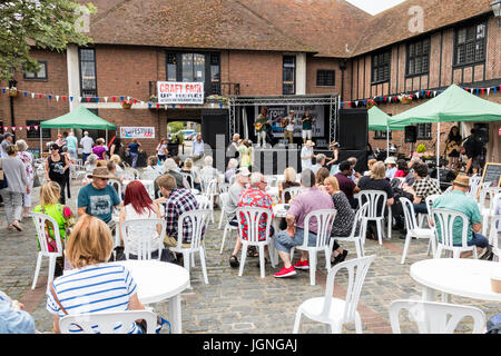 Folk und Ale-Festival Veranstaltung in Sandwich in Kent. Die Leute an den Tischen sitzen auf dem Marktplatz, im Hintergrund der Krise 4, eine lokale folk Gruppe führen Sie auf eine kleine überdachte Bühne. Stockfoto