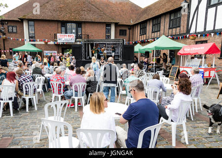 Folk und Ale-Festival Veranstaltung in Sandwich in Kent. Die Leute an den Tischen sitzen auf dem Marktplatz, im Hintergrund der Krise 4, eine lokale folk Gruppe führen Sie auf eine kleine überdachte Bühne. Stockfoto