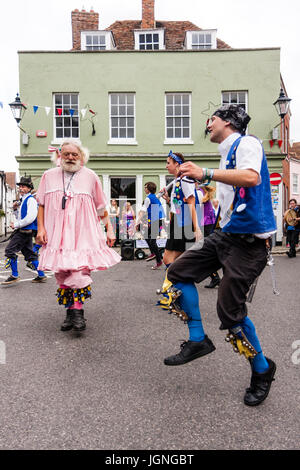 Traditionelle englische Volkstänzer, Royal Liberty Morris Seite tanzen mit ihren 'Idiot' im jährlichen's Sandwich Stadt Folk und Ale-Festival. Morris Narren in Damen rosa Nachthemd bekleidet. Ältere Erwachsene mit Weißbrot und Anschlusslitzen. Stockfoto