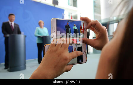 Berlin, Deutschland. 5. Juli 2017. Eine chinesische Journalisten zeichnet eine gemeinsame Presseerklärung der chinesische Präsident Xi Jinping und deutsche Bundeskanzlerin Angela Merkel auf zwei Mobilgeräten in Berlin, Deutschland, 5. Juli 2017. Foto: Wolfgang Kumm/Dpa/Alamy Live News Stockfoto