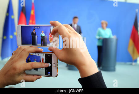 Berlin, Deutschland. 5. Juli 2017. Eine chinesische Journalisten zeichnet eine gemeinsame Presseerklärung der chinesische Präsident Xi Jinping und deutsche Bundeskanzlerin Angela Merkel auf zwei Mobilgeräten in Berlin, Deutschland, 5. Juli 2017. Foto: Wolfgang Kumm/Dpa/Alamy Live News Stockfoto