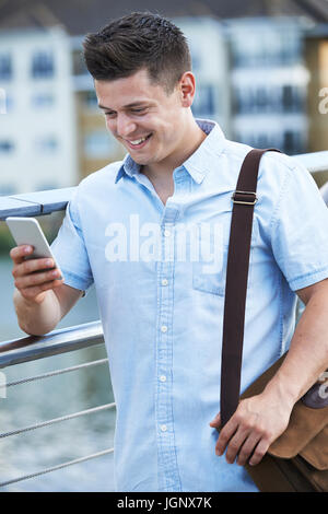 Junger Mann SMS auf Handy zu Fuß zur Arbeit Stockfoto