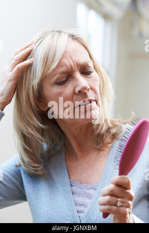 Reife Frau mit Pinsel Corncerned über Haarausfall Stockfoto