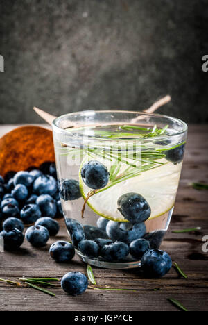 Sommer Erfrischung Ernährung Getränke. Infundiert Detox Wasser mit Rosmarin, Kalk und Heidelbeeren. Rustikalen alten Holztisch Textfreiraum Stockfoto