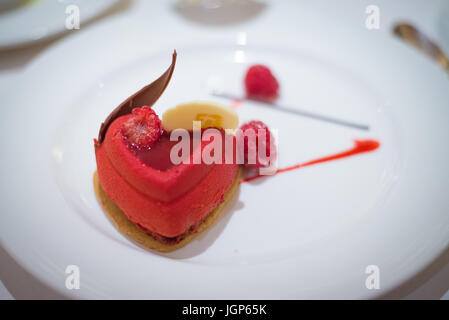 Verplattes Dessert mit Herzmousse auf weißem Teller. Stockfoto