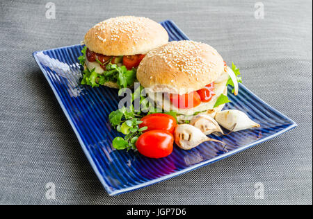 Zwei Belugalinsen und Hanf Samen Burger, mit hausgemachten Salat, Zwiebelringe, Tomaten, hausgemachte Roggen-Brötchen mit Sesam gestapelt. Stockfoto