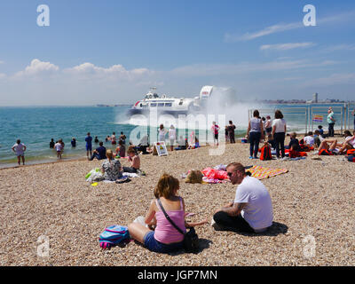 Besucher in Southsea Strand, Portsmouth, genießen Sie einen heißen Sommern Tag als ein Portsmouth nach Isle Of Wight Hovercraft aus der Hoverport betreibt Stockfoto