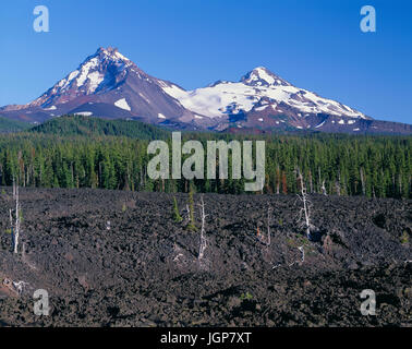 USA, Oregon, drei Schwestern Wildnis, Norden (links) und mittleren Schwester (rechts) Anhöhe jenseits Koniferen und Lavastrom in der Nähe von McKenzie Pass. Stockfoto