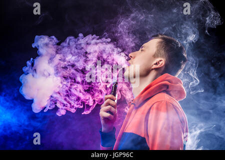 Vaping Mann hält ein Mod. eine Wolke aus Dampf. dunkelblauen Hintergrund. Stockfoto