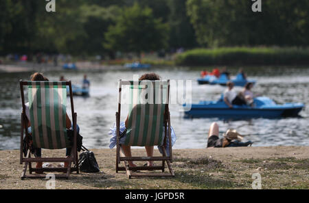 Regents Park, London Besucher entspannen Sie neben einen See mit Booten. Stockfoto