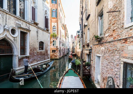 Fassaden der Häuser über einen schmalen Kanal mit Gondeln vorbei in Venedig, Italien Stockfoto