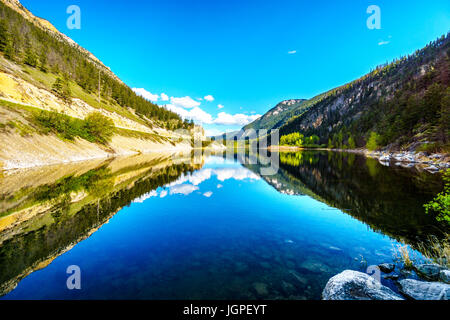 Blauer Himmel, Bäume und Berge reflektieren die glatte Oberfläche auf dem kristallklaren Wasser des Krone-Sees entlang Highway 99 in Marble Canyon, BC, Kanada Stockfoto